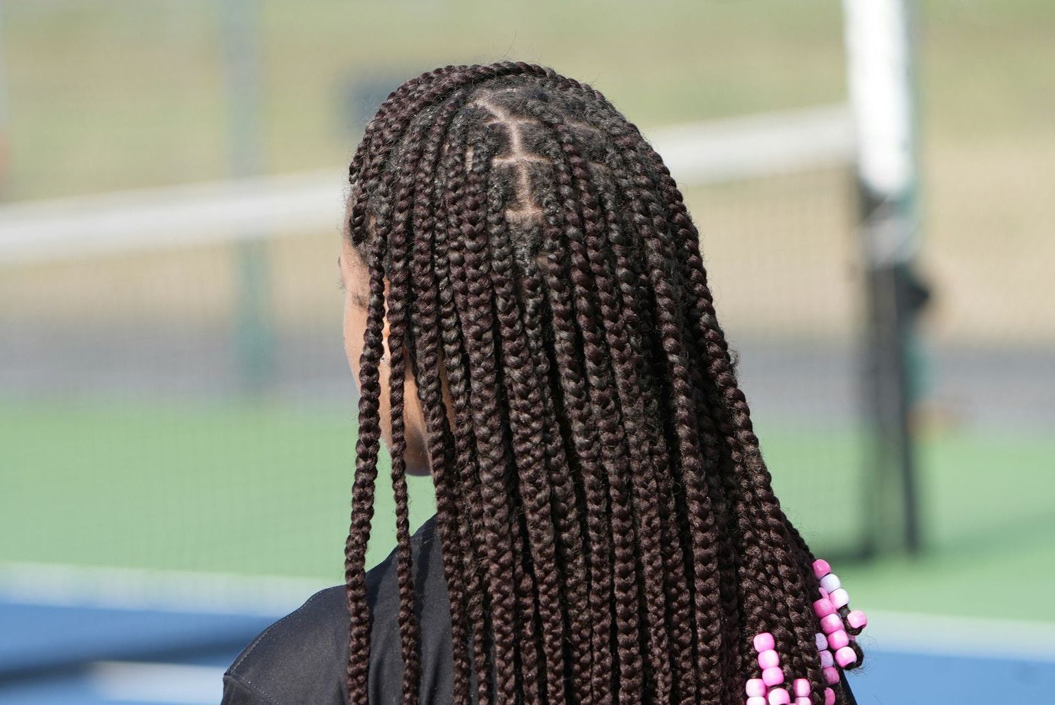 a woman with long box braids on a tennis court
